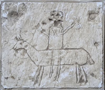 une plaque en pierre sur laquelle est représenté un homme chevauchant une chèvre