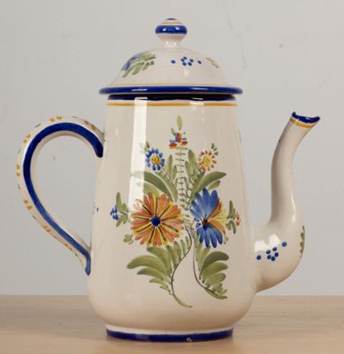 une théière blanche ornée de fleurs bleues et jaunes