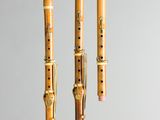 trois clarinettes en bois sont alignées sur un fond gris