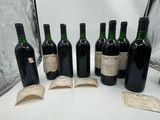 several bottles of wine are lined up on a table next to an open book