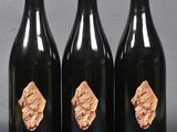three bottles of wine with gold foil on them sitting on a table