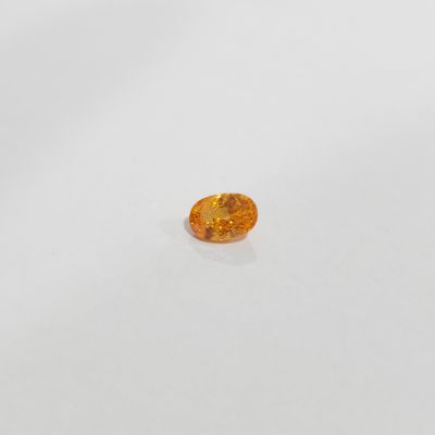 an orange sapphire stone on a white surface