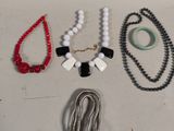 plusieurs colliers et bracelets disposés sur une surface blanche