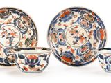 three cups and a saucer sitting on a white surface