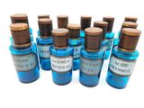 Plusieurs bouteilles contenant un liquide bleu et munies de bouchons en bois sont alignées