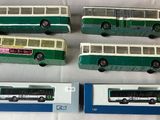 four green and white bus models on a white surface