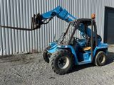 un chariot élévateur bleu garé devant un immeuble
