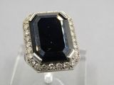 a close up of a ring with a black stone surrounded by white diamonds