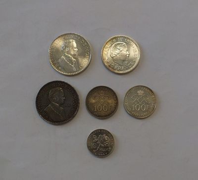 several different coins are arranged on a white surface