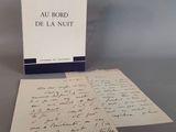 un livre ouvert posé sur une table à côté d'une feuille de papier