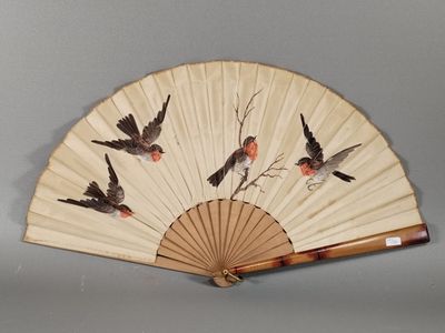 un éventail orné d'oiseaux, posé sur une table