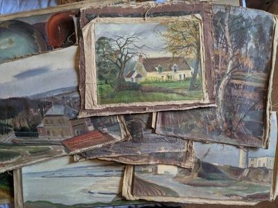 une pile de tableaux posée sur un lit recouvert d'une couette bleue