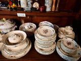many plates and bowls sitting on a shelf in a room