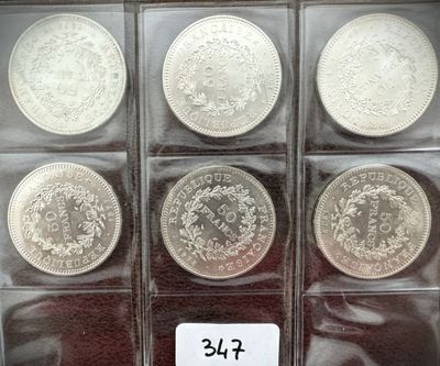 six pièces d'argent dans une vitrine, accompagnées d'une étiquette de prix