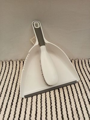 a white dust pan with a black handle on a striped table cloth