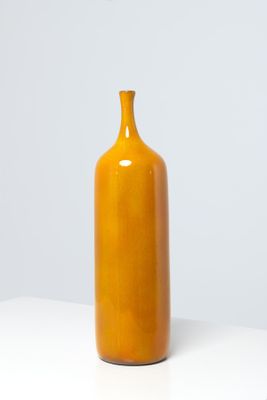 a yellow vase that is sitting on a white table