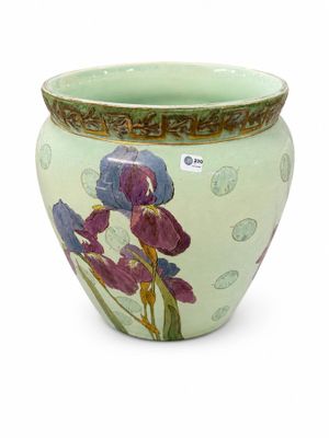 un vase vert orné de fleurs violettes, posé sur un fond blanc