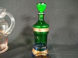 a green glass bottle with a cork stopper next to a glass pitcher