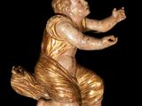 a statue of a baby sitting on a black surface