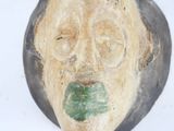 a wooden mask with a green leaf on it