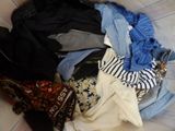 a pile of clothes sitting on a bed next to a pair of shoes