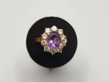 a close up of a ring with a purple stone surrounded by diamonds
