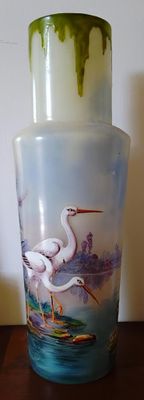 un vase en verre avec un tableau posé sur une table