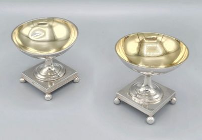 paire de bougeoirs plaqués argent sur des socles, sur fond gris
