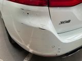 the rear end of a white car with scratches on it ' s bumper