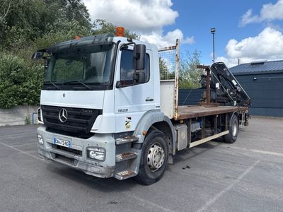 un camion blanc avec une grue à l'arrière dans un parking