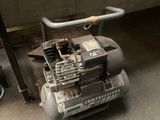 un petit compresseur d'air posé par terre dans un garage