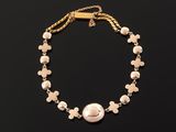 a white pearl and gold bracelet on a black background