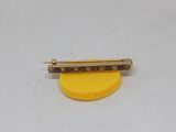 yellow and red diamond bar broochle pin on a white surface