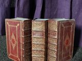 deux vieux livres posés sur une table, à côté d'un rideau violet