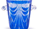un vase en verre bleu muni d'une anse, sur fond blanc