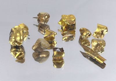 Plusieurs pièces d'or sont exposées sur une surface blanche