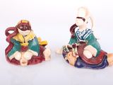 two figurines of a woman and a man sitting on the ground