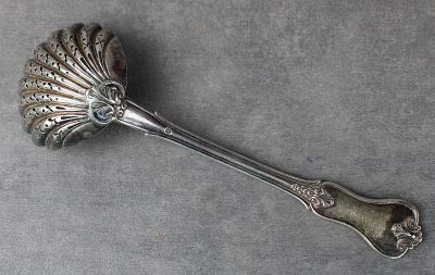 une cuillère en argent posée sur une surface grise
