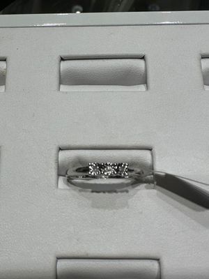 une bague en diamant dans une boîte blanche, accompagnée d'une paire de pinces