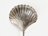 a silver shell shaped object on a white surface