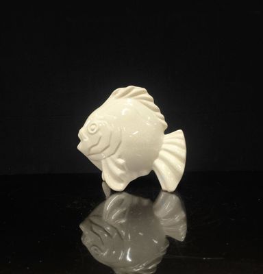 une figurine blanche représentant un poisson sur un fond noir