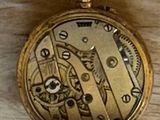 a gold pocket watch sitting on top of a wooden table