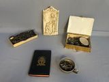 une petite boîte remplie de pièces et un petit livre posés sur une table