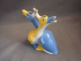 a small blue and yellow bird figurine on a gray surface