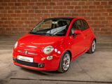 a small red car parked in front of a brick wall