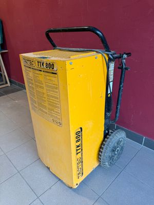 une boîte jaune posée par terre à côté d'un chariot noir