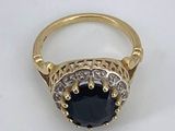 an image of a gold ring with a black stone surrounded by white diamonds