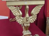 une table dorée sur laquelle se trouve un oiseau, posée sur une table rouge
