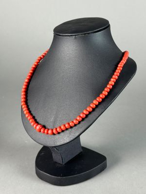 a red beaded necklace on a black mannequin stand