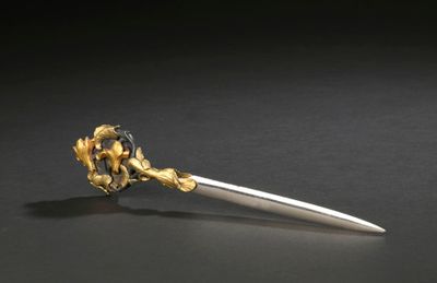 a silver and gold flower on top of a knife
